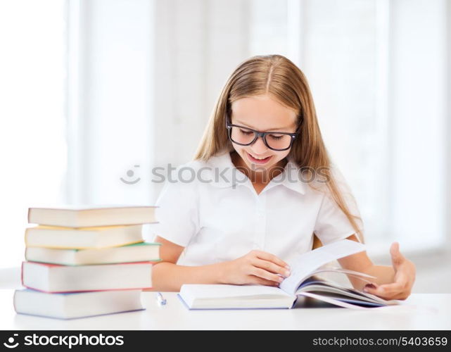 education and school concept - little student girl studying and reading books at school