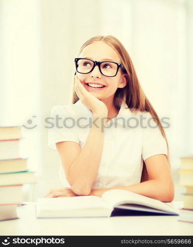education and school concept - little student girl studying and reading books at school