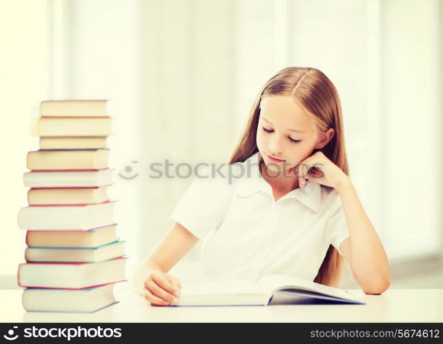 education and school concept - little student girl studying and reading books at school