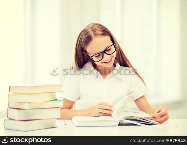 education and school concept - little student girl studying and reading books at school