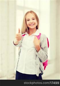 education and school concept - little student girl with bag showing thumbs up at school