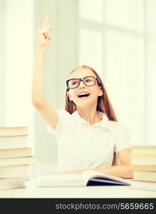 education and school concept - little student girl with books raising hand up at school