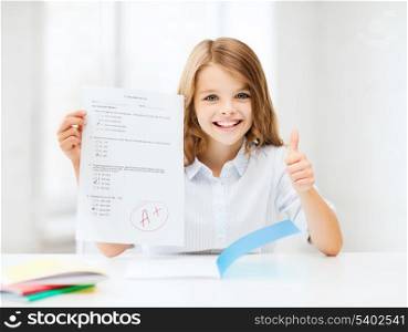 education and school concept - little student girl with test and A grade showing thumbs up at school