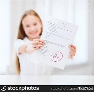 education and school concept - little student girl with test and A grade at school showing thumbs up