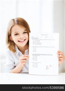 education and school concept - little student girl with test and grade at school