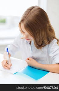 education and school concept - little student girl writing in notebook at school