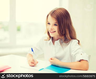 education and school concept - little student girl writing in notebook at school