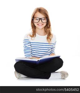 education and school concept - smiling little student girl with book and eyeglasses sitting on the floor