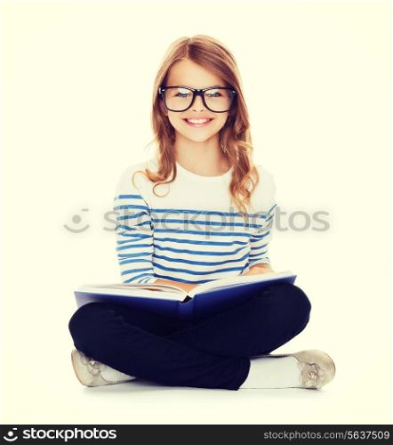 education and school concept - smiling little student girl with book and eyeglasses sitting on the floor