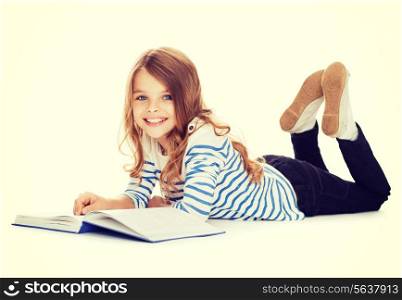 education and school concept - smiling little student girl with book lying on the floor