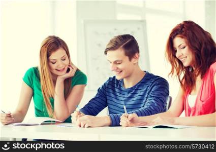 education and school concept - three smiling students with textbooks at school