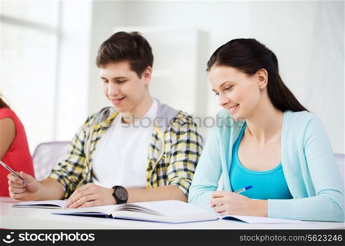 education and school concept - two smiling students with textbooks and books at school