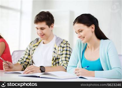 education and school concept - two smiling students with textbooks and books at school