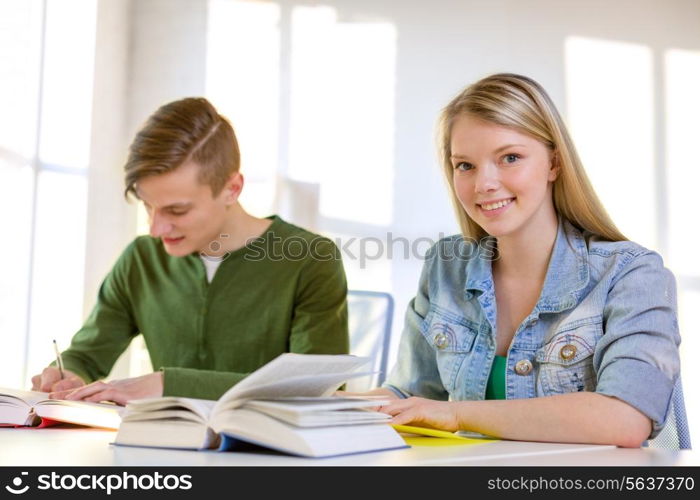 education and school concept - two smiling students with textbooks and books at school