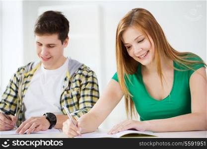 education and school concept - two smiling students with textbooks at school