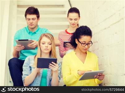 education and technology concept - calm students with tablet pc computer sitting on staircase
