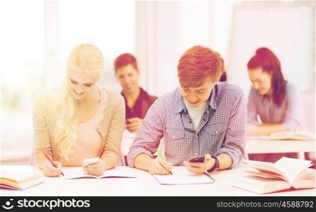 education and technology concept - group of students looking into smartphone at school. students looking into smartphone at school