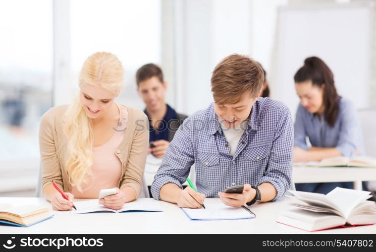 education and technology concept - group of students looking into smartphone at school