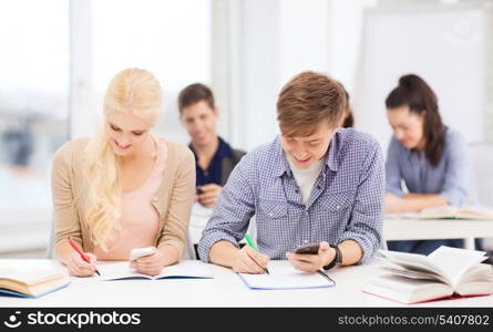 education and technology concept - group of students looking into smartphone at school