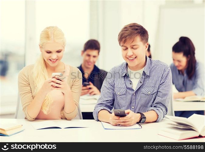 education and technology concept - group of students looking into smartphone at school