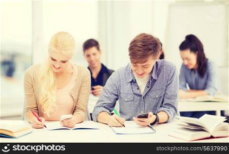 education and technology concept - group of students looking into smartphone at school