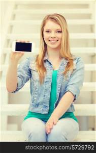 education and technology concept - smiling female student showing smartphone blank screen sitting on staircase