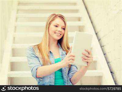 education and technology concept - smiling female student with tablet pc computer sitting on staircase