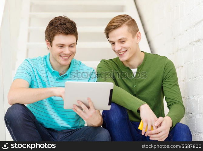 education and technology concept - smiling male students with tablet pc computer sitting on staircase
