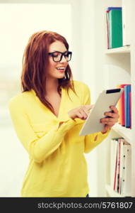 education and technology concept - smiling redhead female student in eyeglasses with tablet pc computer in library