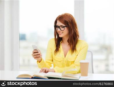 education and technology concept - smiling student girl in eyeglasses with smartphone, books and takeaway coffee at school
