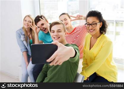 education and technology concept - smiling students making picture with tablet pc computer at school