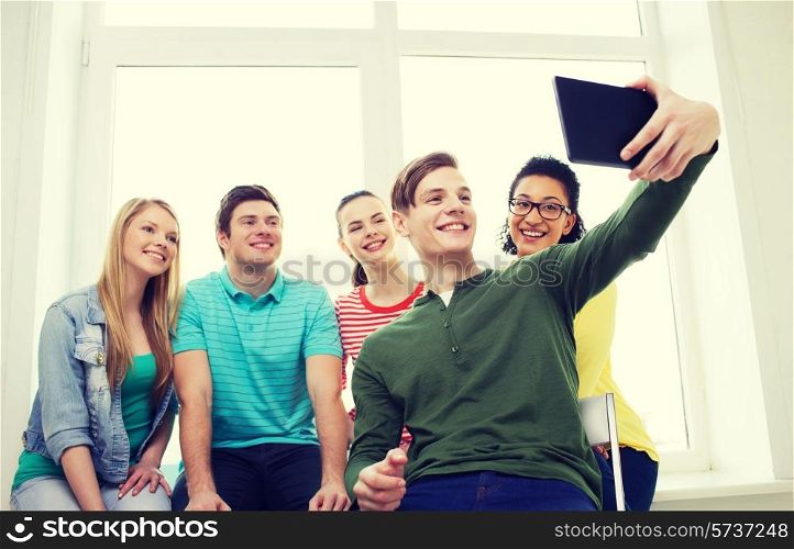 education and technology concept - smiling students making picture with tablet pc computer at school
