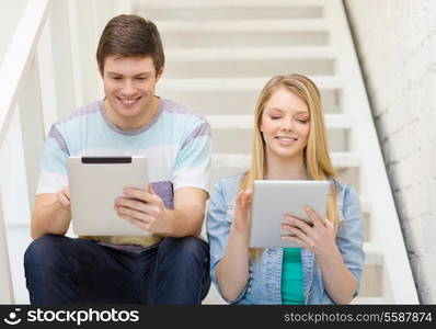 education and technology concept - smiling students with tablet pc computer sitting on staircase