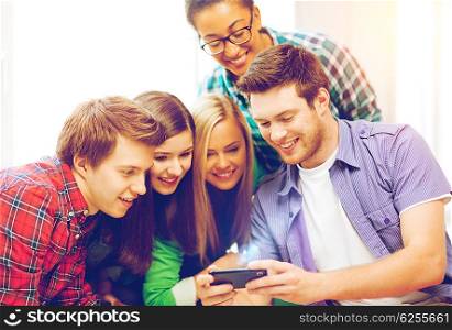 education and technology - group of students looking at smartphone at school. students looking at smartphone at school