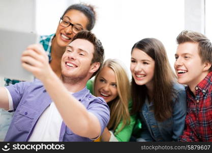 education and technology - group of students taking selfie with tablet pc at school