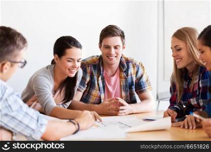 education, architecture and people concept - group of smiling students with blueprint meeting indoors. group of smiling students with blueprint