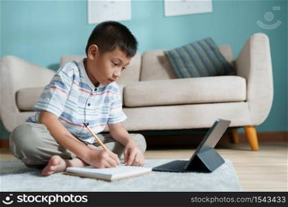 Education. Asian boy learning and doing homework with the online teacher on tablet digital at home