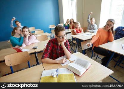 education, bullying, conflict, social relations and people concept - student boy in glasses reading book and suffering of classmates mockery at school