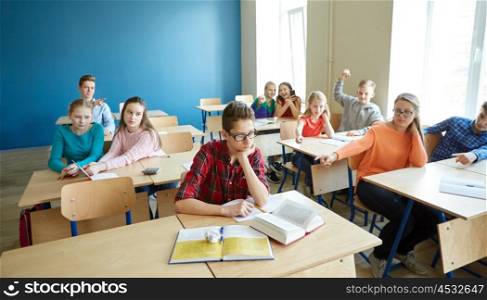 education, bullying, conflict, social relations and people concept - student boy in glasses reading book and suffering of classmates mockery at school