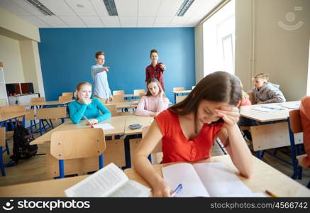 education, bullying, conflict, social relations and people concept - students teasing and judging girl classmate behind her back at school