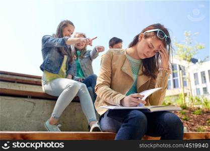 education, bullying, high school, social relations and people concept - unhappy student girl with book suffering of classmates mockery