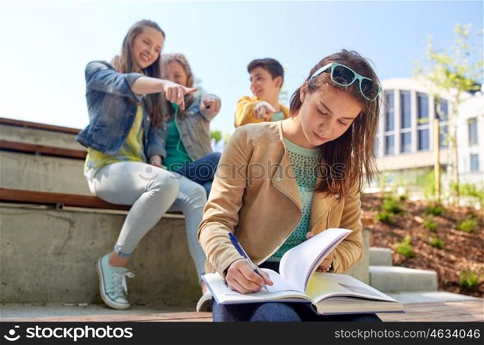 education, bullying, high school, social relations and people concept - unhappy student girl with book suffering of classmates mockery. student girl suffering of classmates mockery