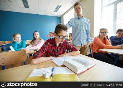 education, bullying, social relations and people concept - classmate offending at student boy at school