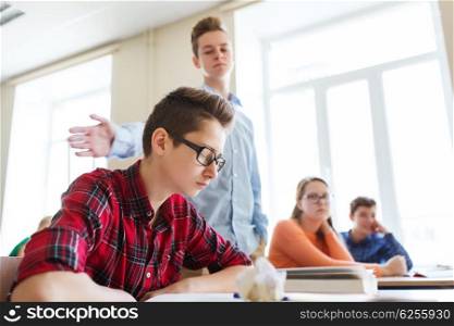 education, bullying, social relations and people concept - classmate offending at student boy at school
