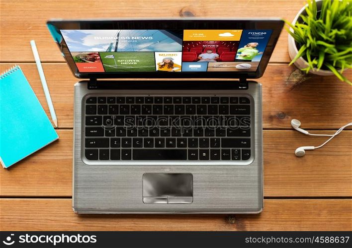 education, business and technology concept - close up of laptop computer with internet news on screen on wooden table