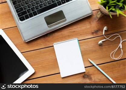 education, business and technology concept - close up of notebook with on laptop computer and tablet pc on wooden table
