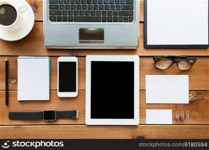 education, business and technology concept - close up of on laptop computer, tablet pc, notebook and smartphone on wooden table