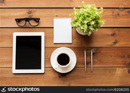 education, business and technology concept -close up of tablet pc computer, coffee cup, eyeglasses and notepad on wooden table