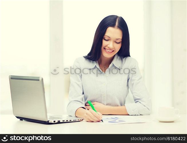 education, business and technology concept - smiling businesswoman or student with laptop computer, charts and coffee