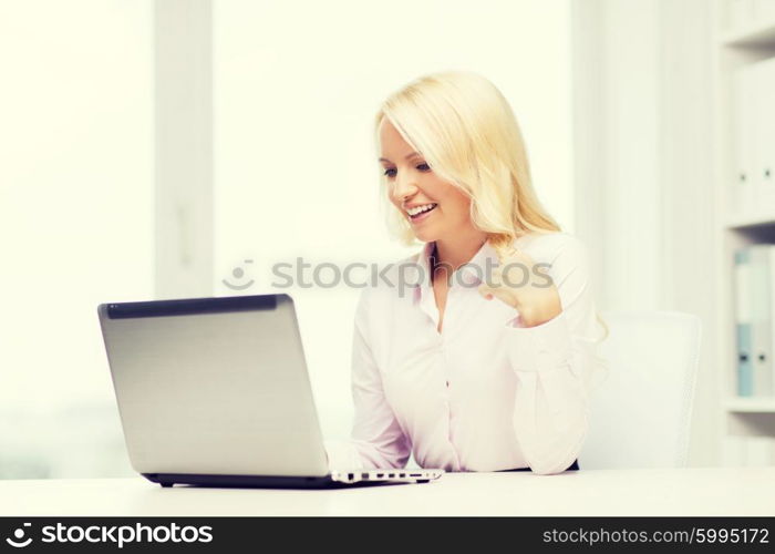 education, business and technology concept - smiling businesswoman or student with laptop computer in office